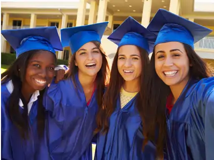 Four girls in blue graduation gowns smiling for the camera